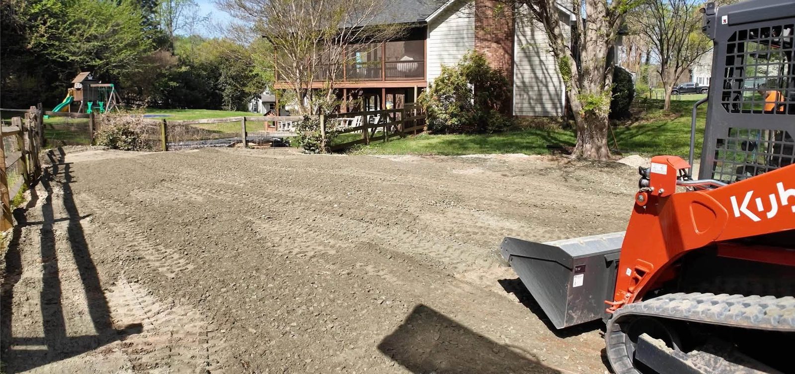 A compact track loader grading a yard flat.